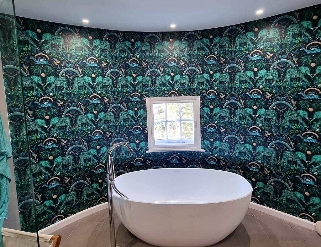 Freestanding bath in front of a statement wallpaper wall.