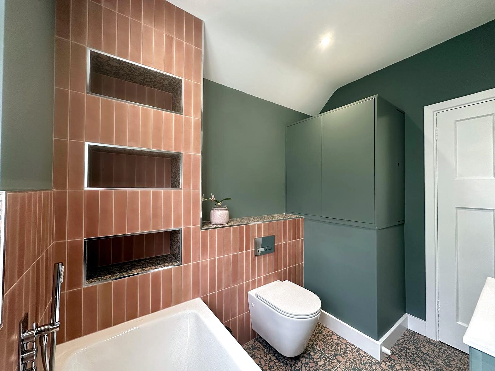 Pink strip tiles with built-in niches and a terrazzo floor.