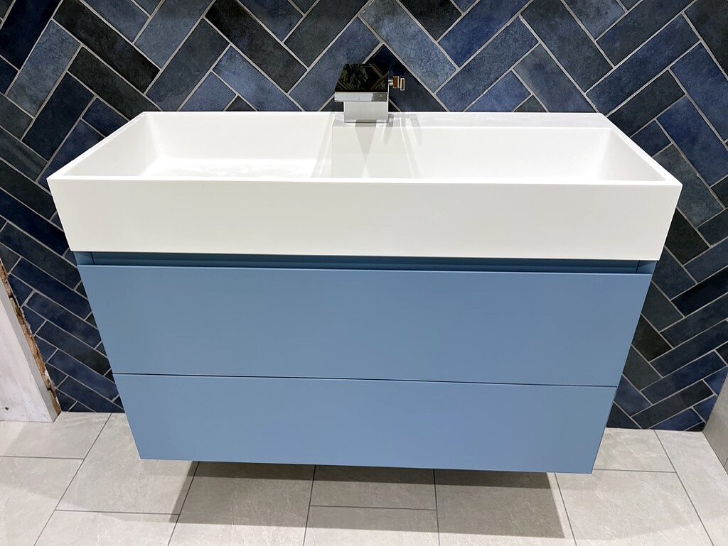 Blue tiles laid in herringbone behind a floating vanity.