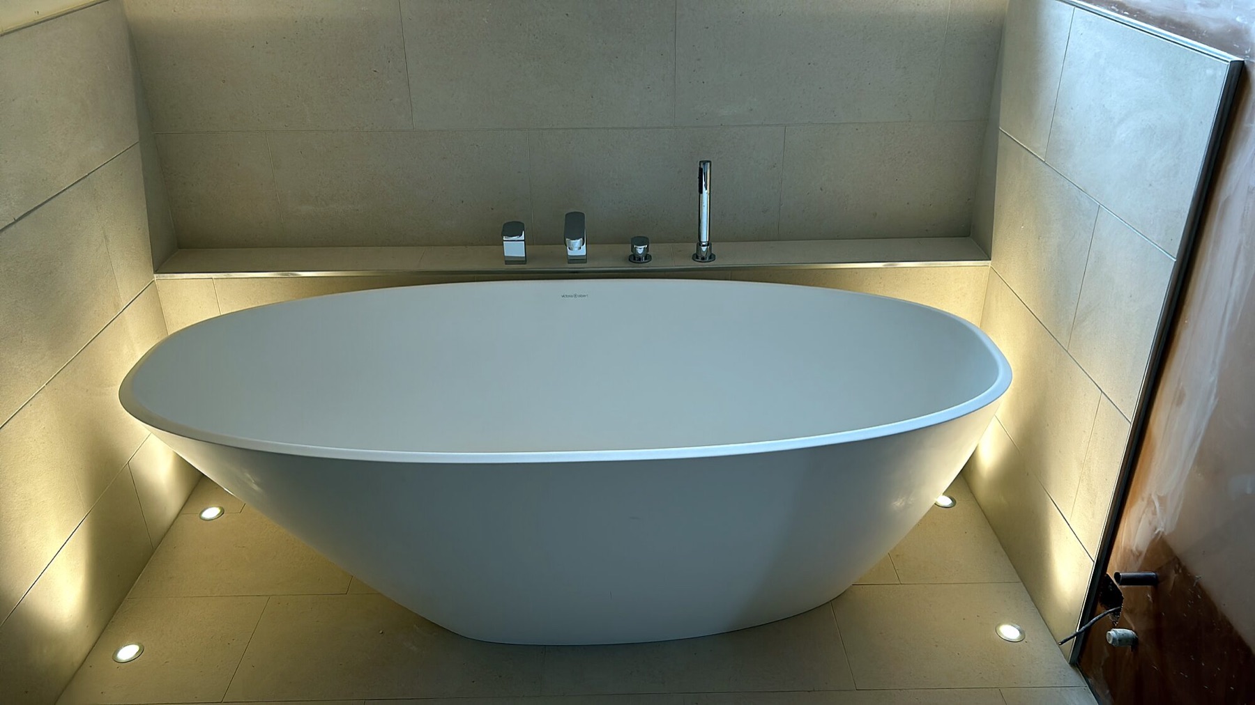 Freestanding bath set into a lit alcove.