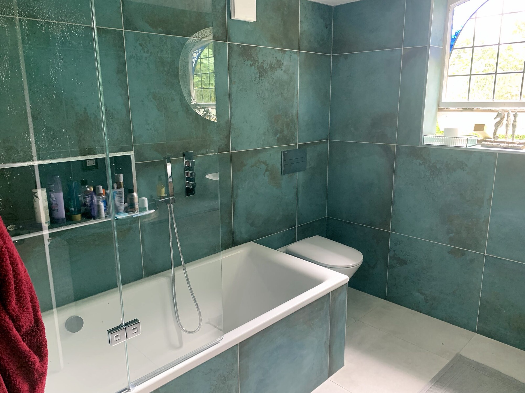 Large green metallic-glaze tiles around a bath and shower.